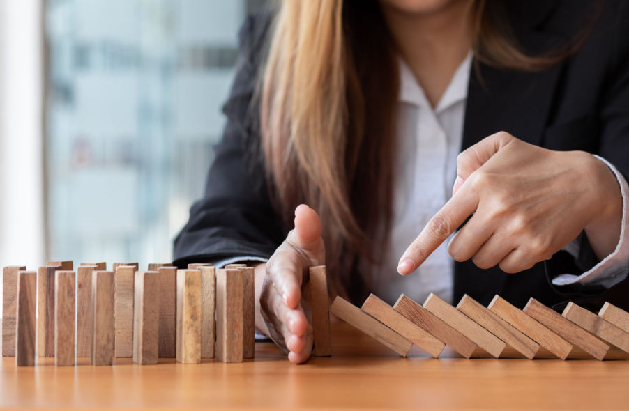 businesswoman protect wooden block fall to another