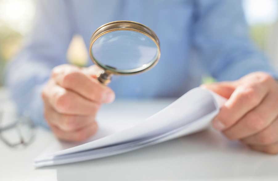 businessman reading documents with magnifying glass